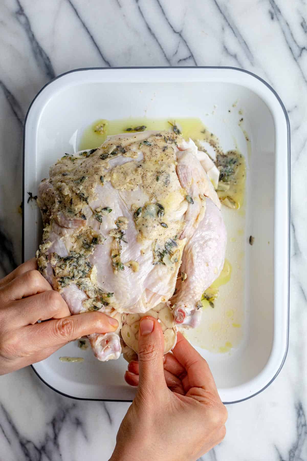 Adding a head of garlic inside whole chicken.