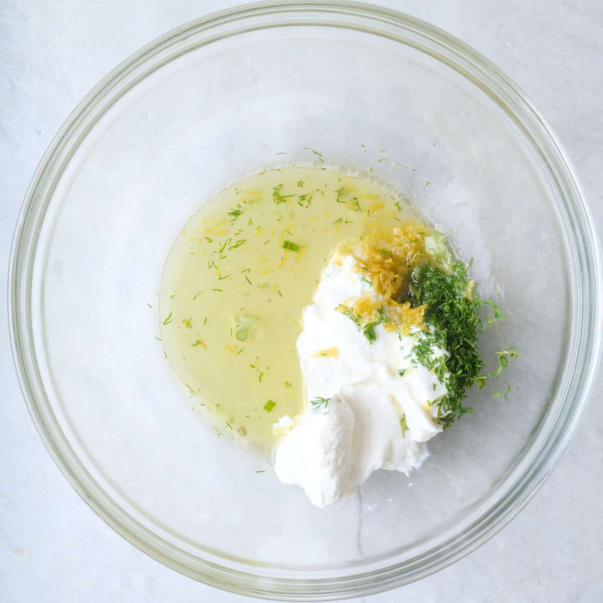 Oil, yogurt, lemon, and dill in a bowl.