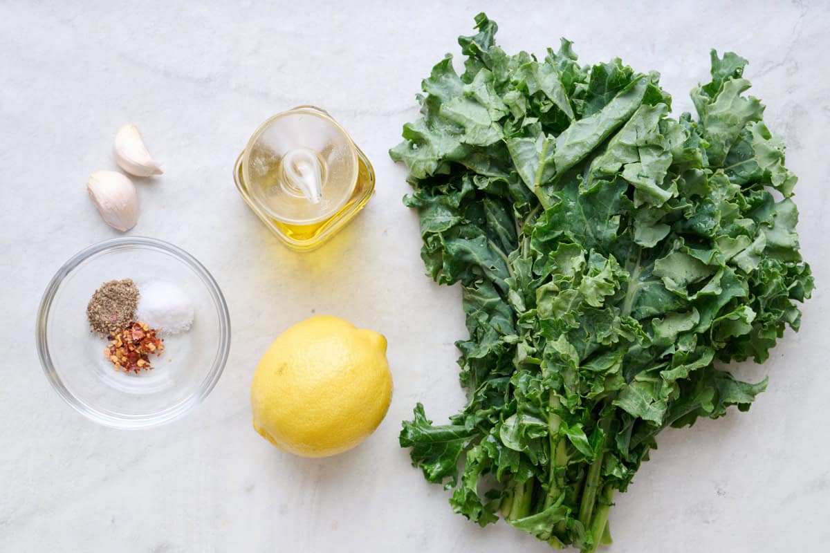 Ingredients for recipe: seasonings, garlic, oil, lemon, and kale.