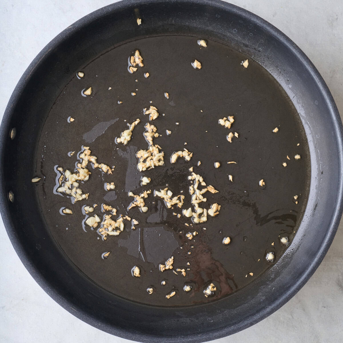 Oil and garlic in a large skillet after sautéing.