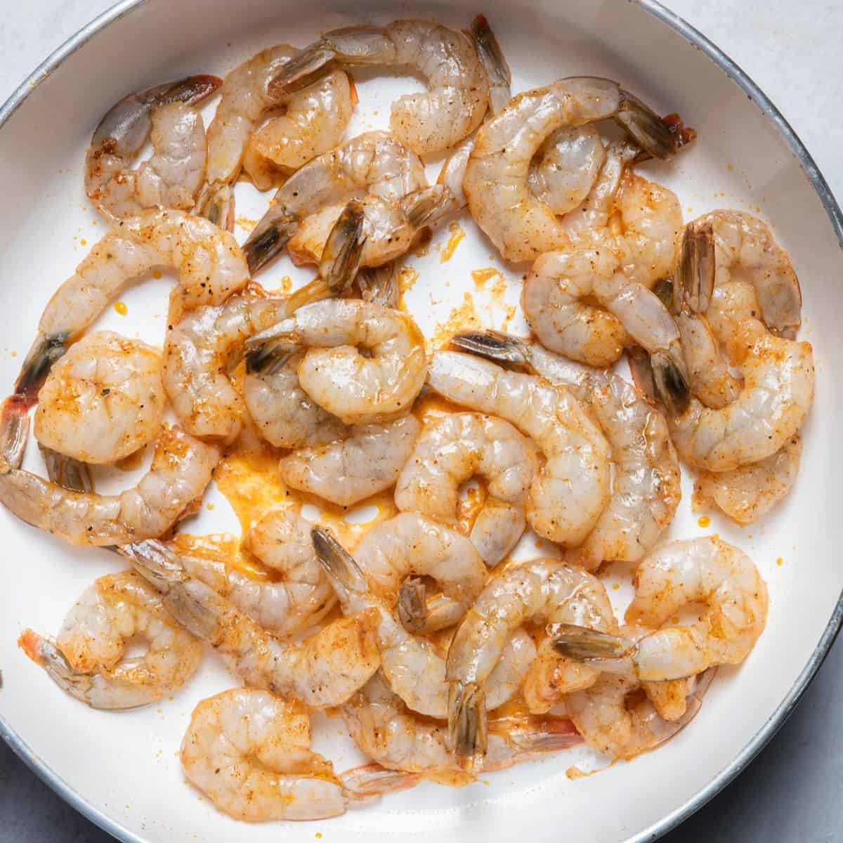 Seasoned shrimp in a skillet before cooking.