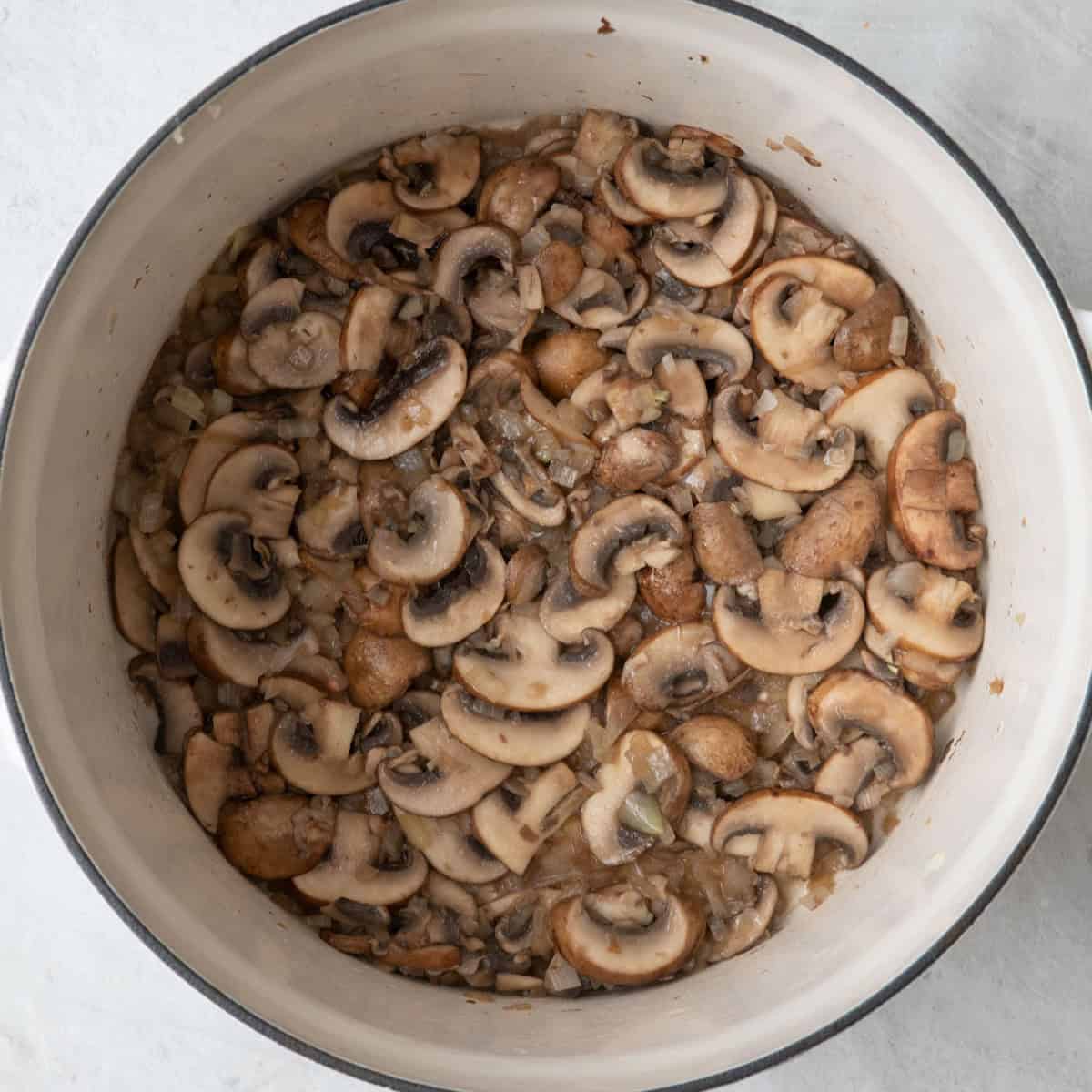 Dutch oven with cooked onions and mushrooms.