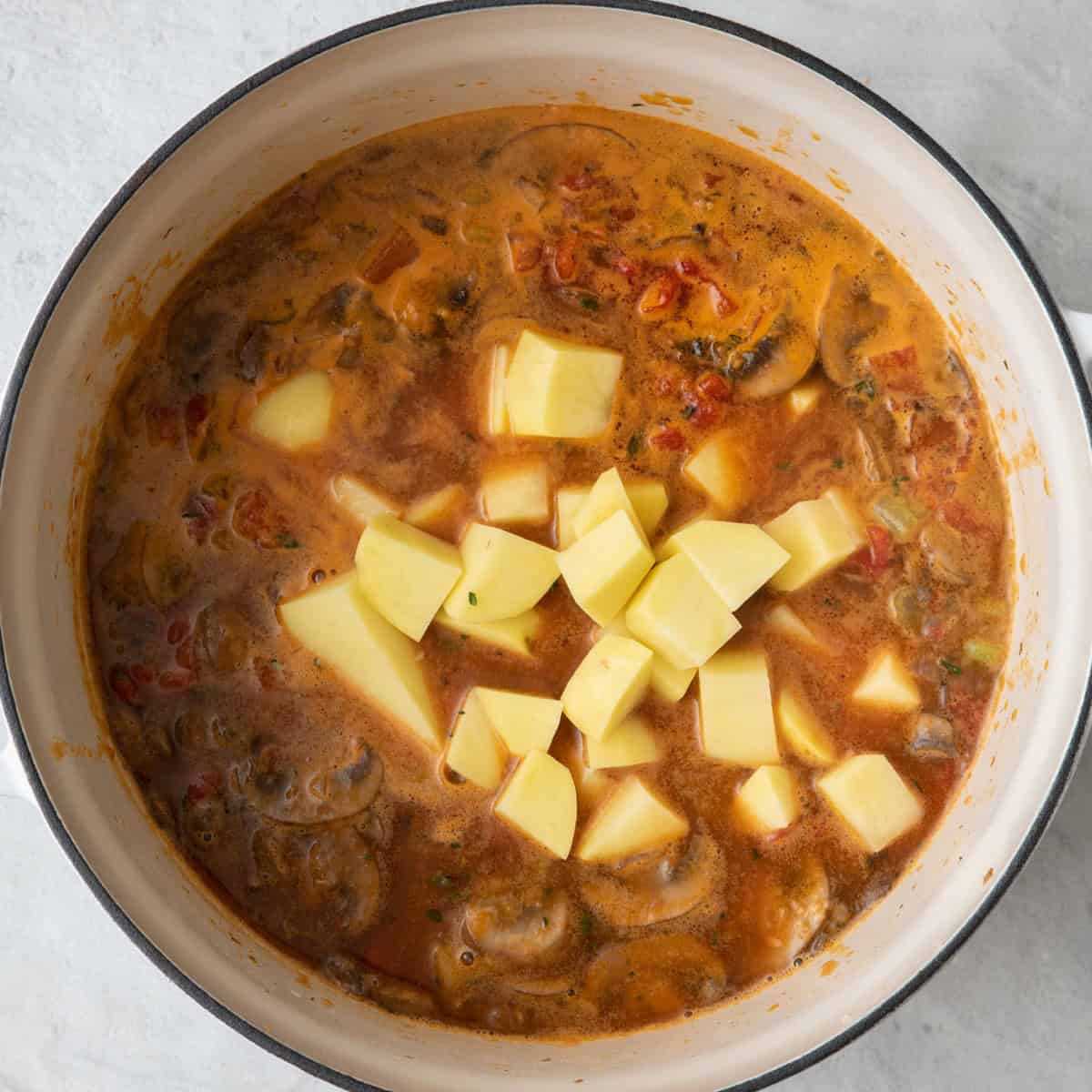 Diced tomatoes and broth stirred in and potatoes added on top.