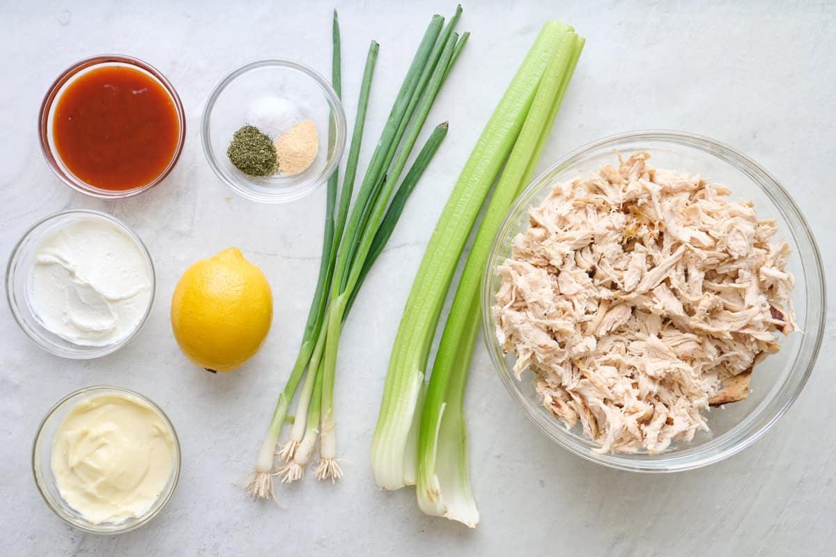 Ingredients for recipe: Greek yogurt, mayo, hot sauce, lemon juice, dried dill, garlic powder, salt, shredded chicken breast, celery, and green onions.