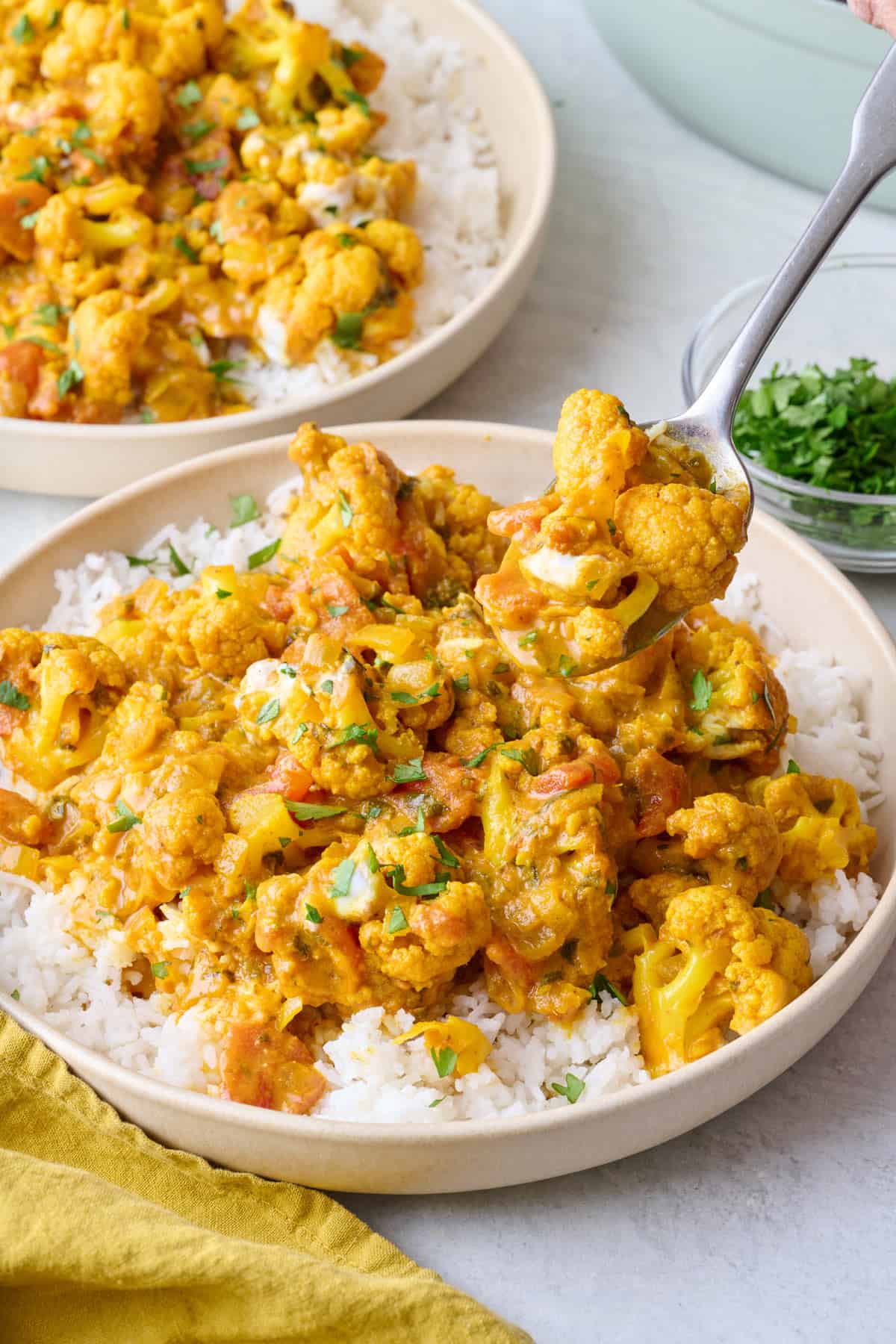 Spoon lifting up a bite of cauliflower curry.