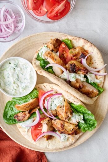 two open faced chicken gyro recipe with lettuce, tomatoes, onions, and home tzatziki sauce.