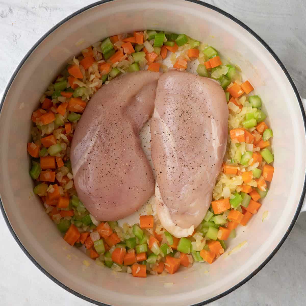 Cooked veggies and garlic to the side with chicken in the middle seasoned with salt, pepper and thyme.