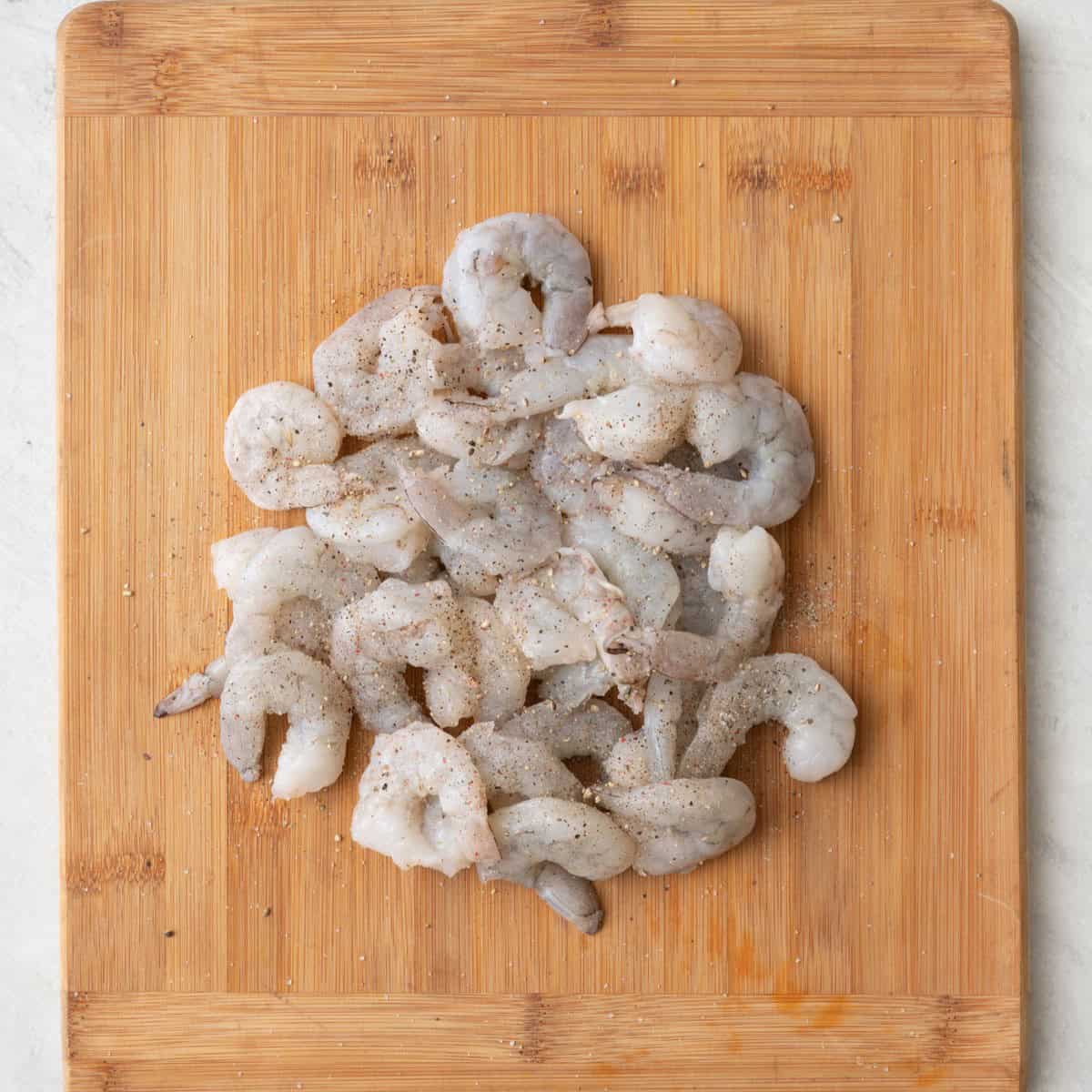 Shrimp on cutting board with seasoning.