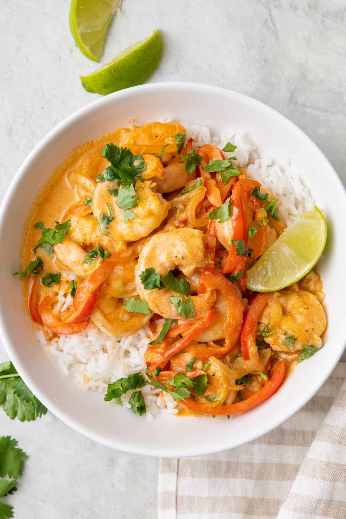 Red curry coconut shrimp served over rice in a bowl.