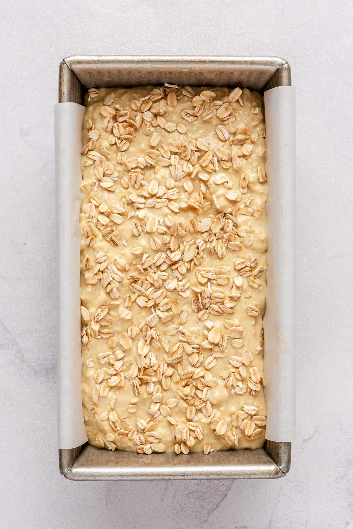 Batter added to prepared loaf pan with some extra oats added on top.