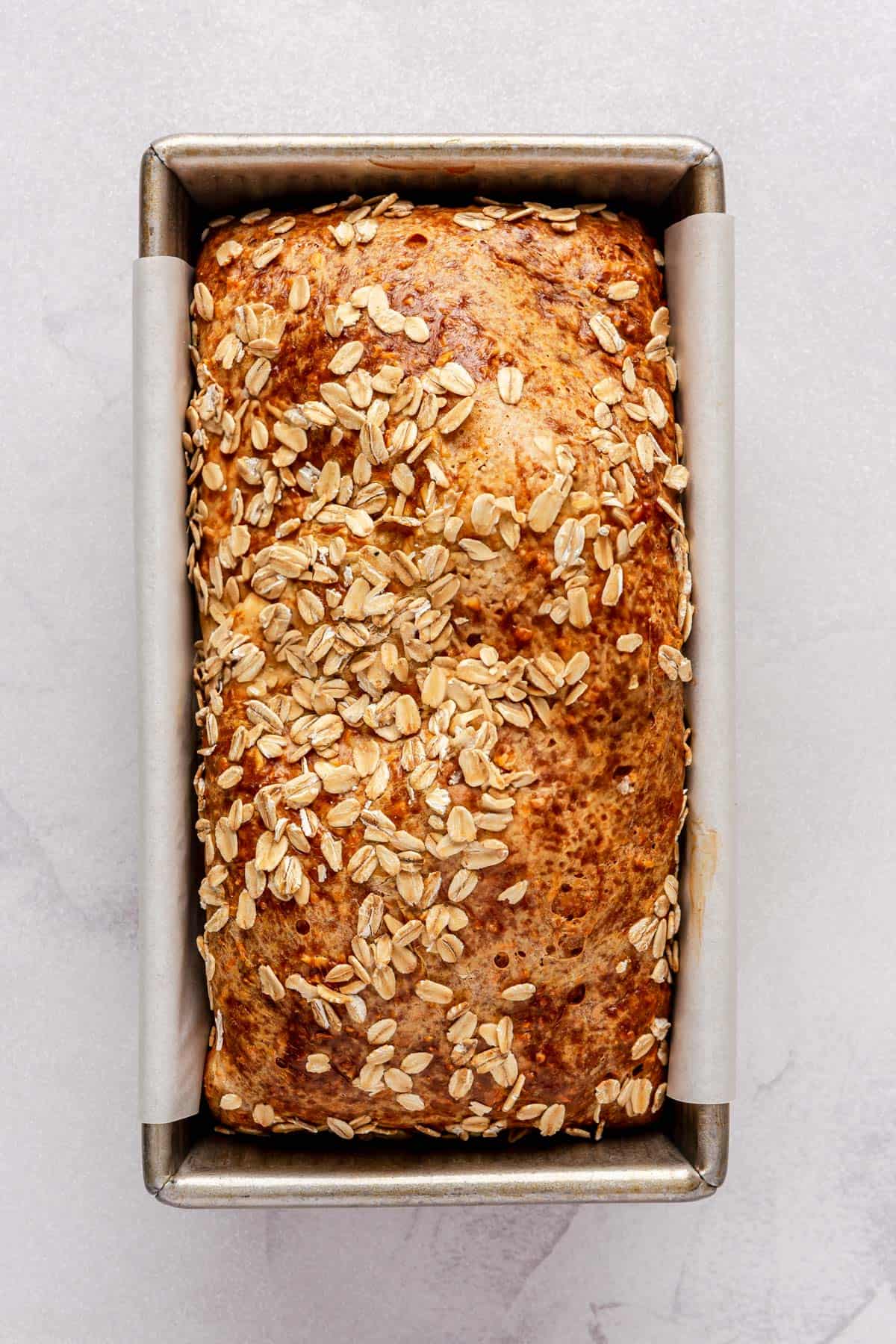 Bread after baking with a golden top in loaf pan.