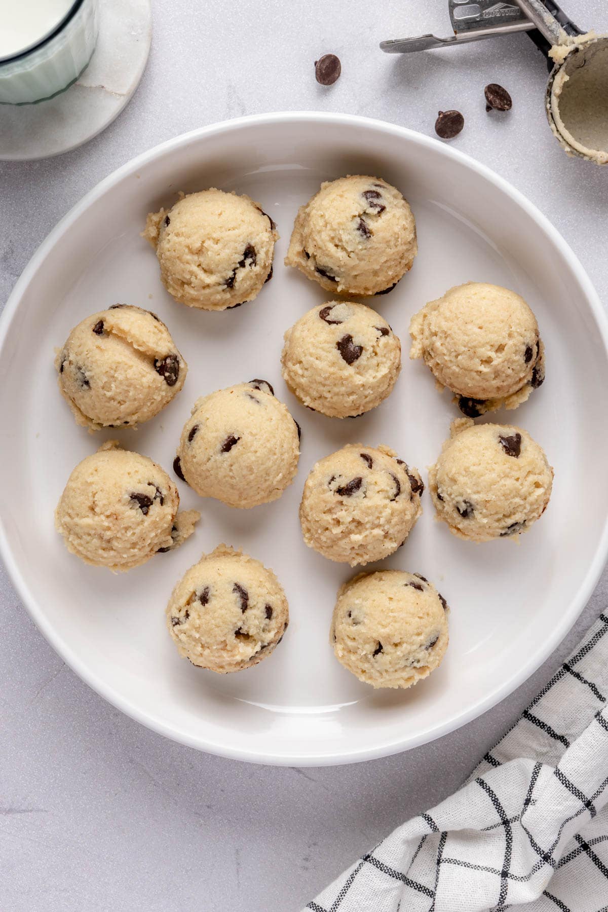 High protein cookie dough balls made with cottage cheese in a bowl with cookie school nearby.