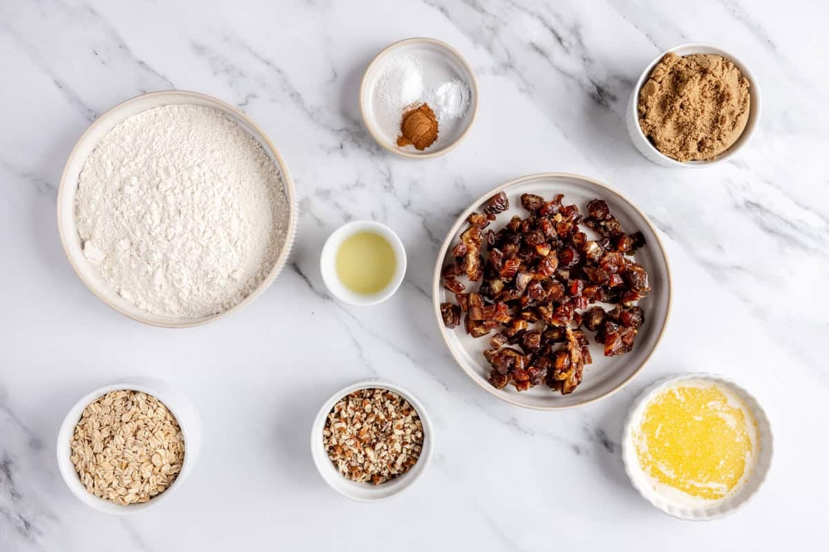 Ingredients for recipe: flour, oats, pecans, lemon juice, dates, salt, cinnamon, baking soda, brown sugar, and melted butter.