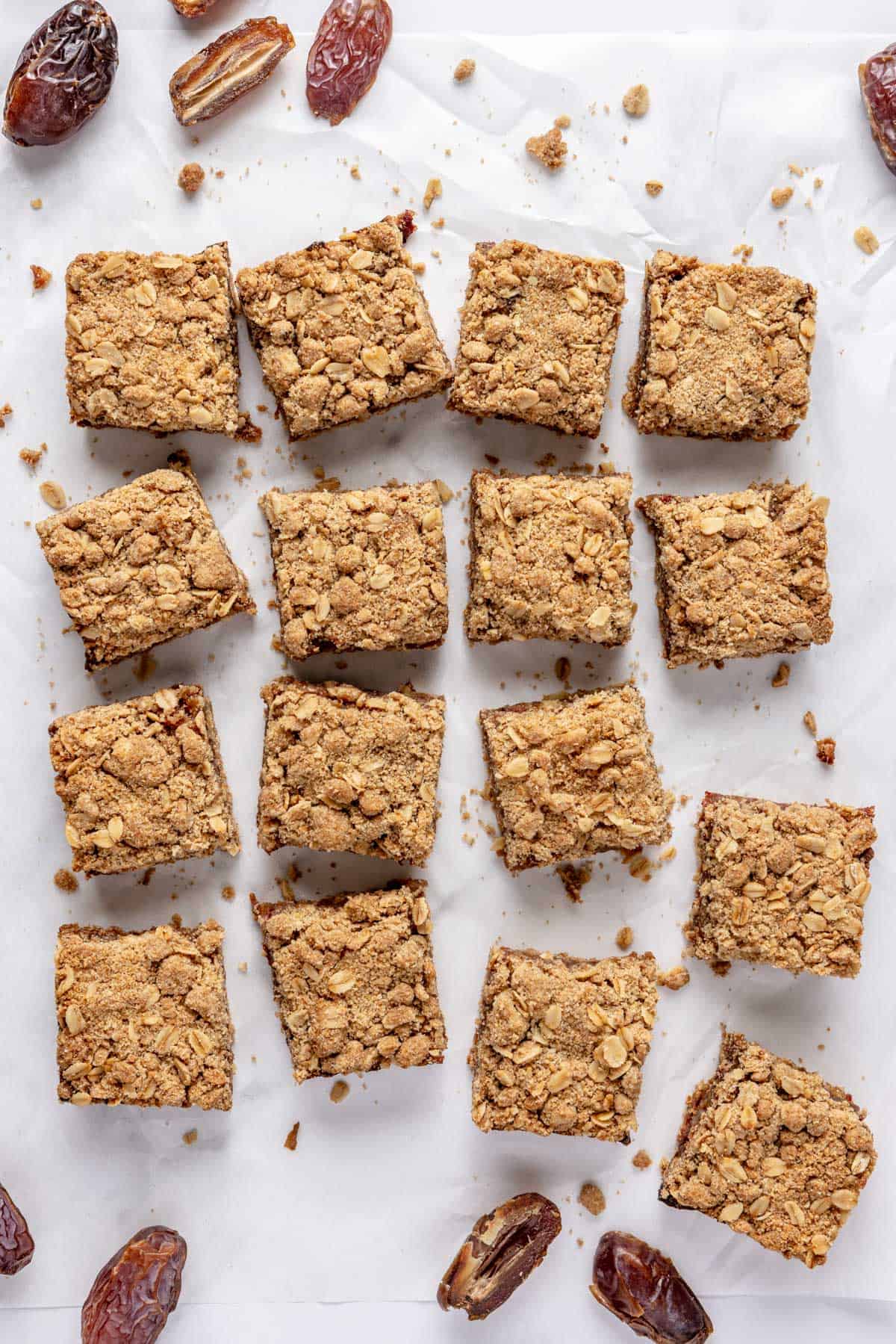 Date bars removed from pan on parchment paper and cut into 16 squares with a few squares pulled away, extra whole pitted dates around.