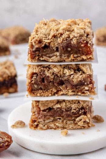 3 date bars stacked with a small piece of parchment between each one, remaining bars nearby.