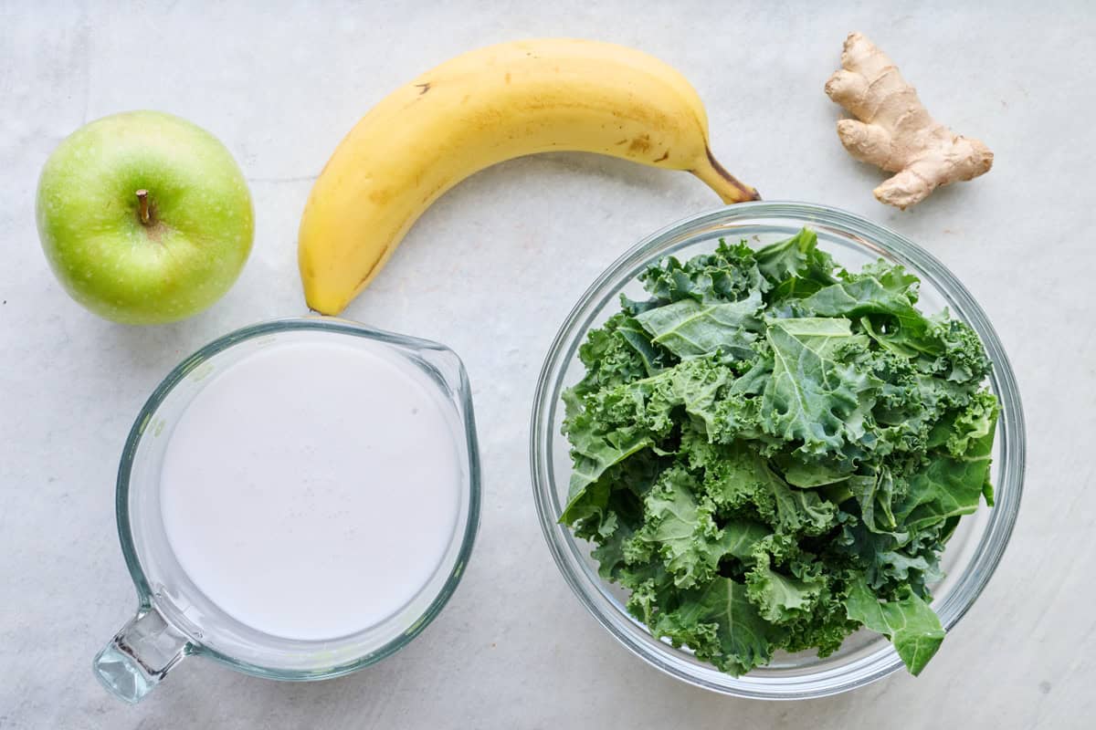 Ingredients for recipe: apple, milk, banana, kale, and ginger.