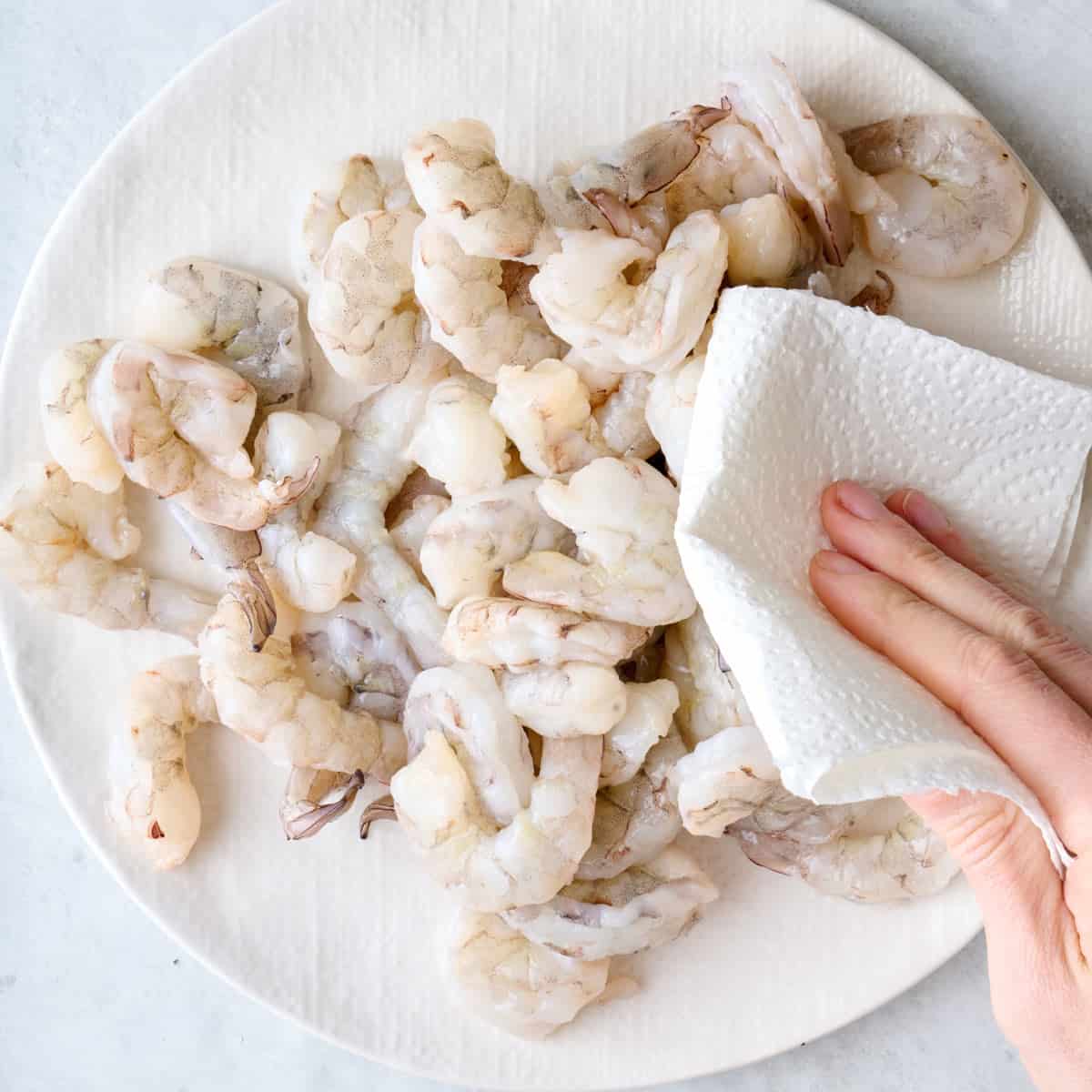 Patting shrimp dry with paper towels.