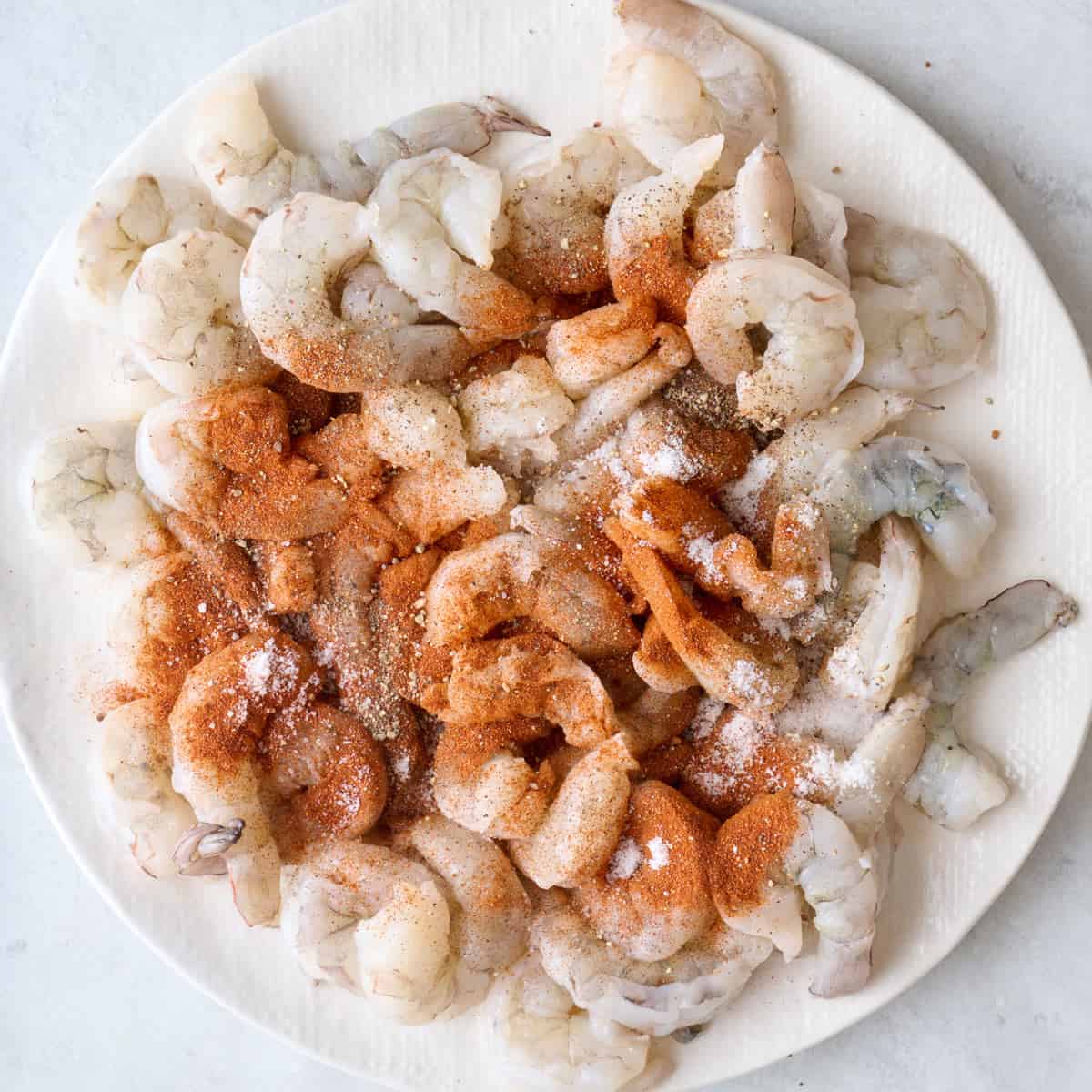 Shrimp on plate with salt, pepper, and paprika added.