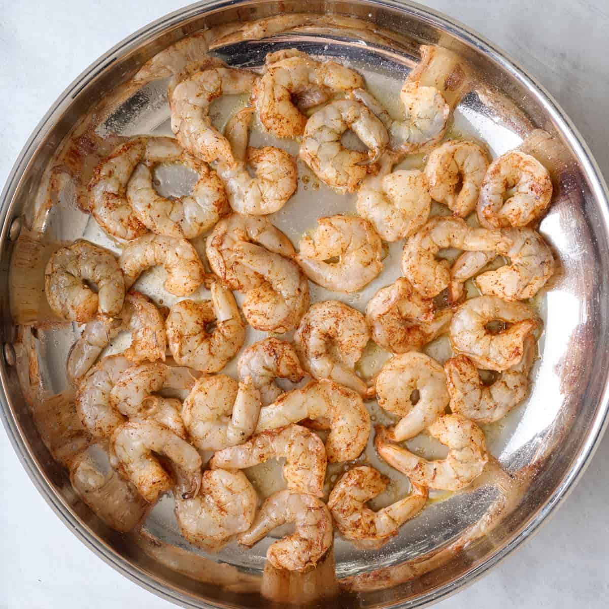 Large skillet with seasoned shrimp added before cooked.