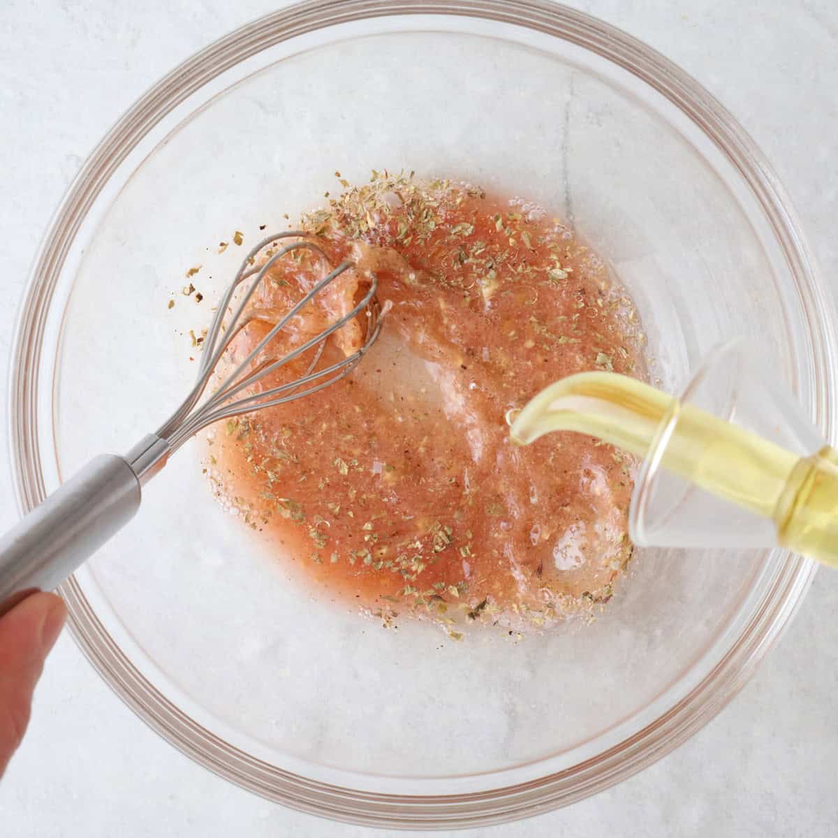 Whisking dressing while pouring in oil.