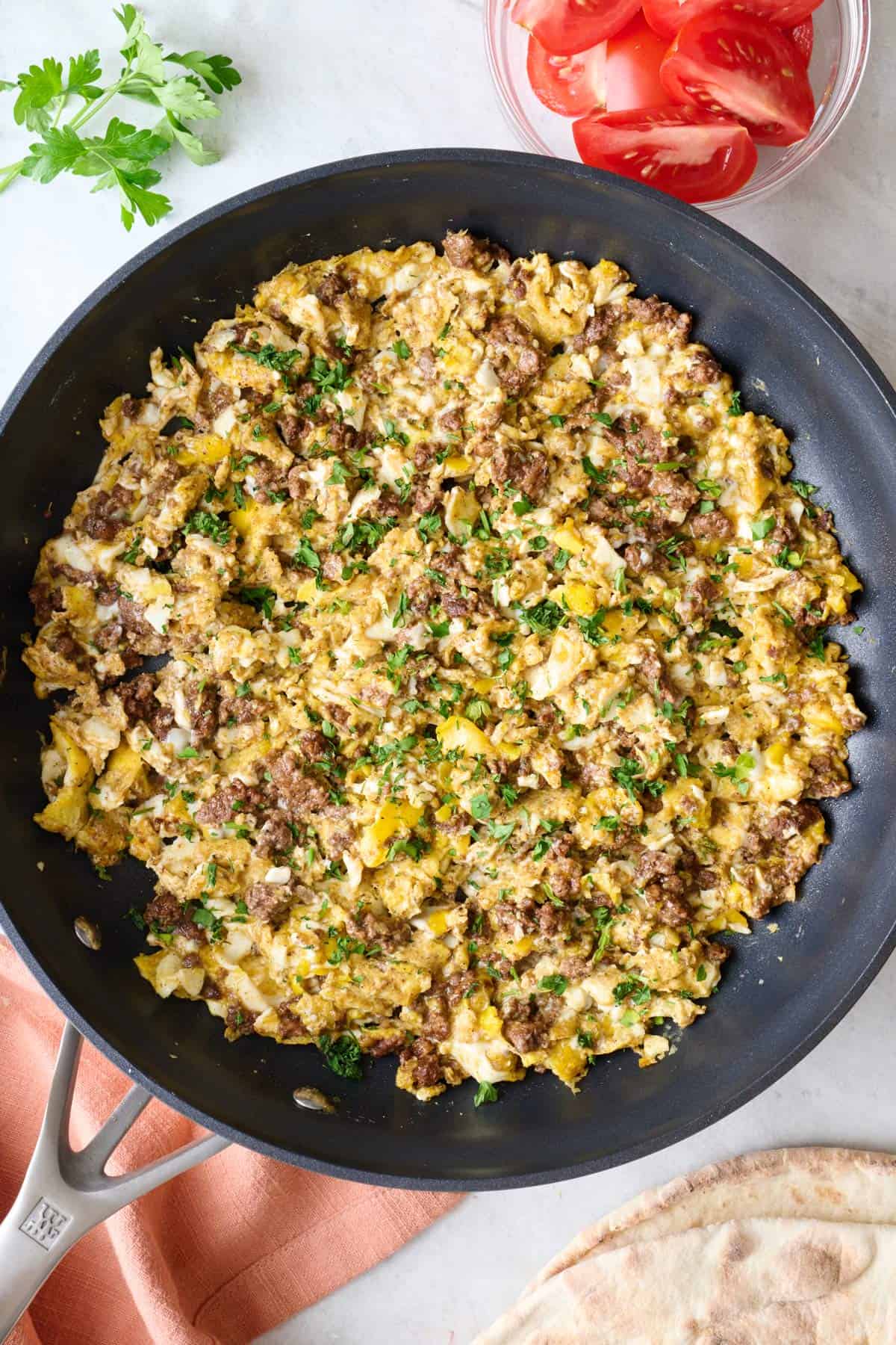 Ground beef and scrambled eggs in a skillet garnished with fresh parsley.