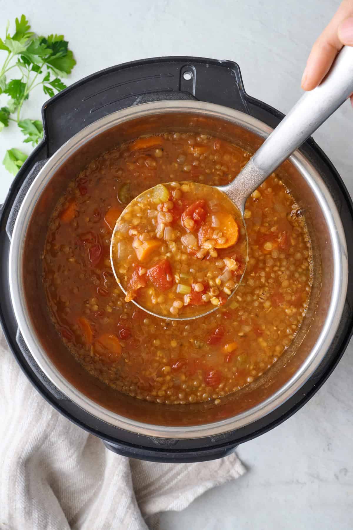 Lentil soup in an Instant Pot with ladle lifting some up.