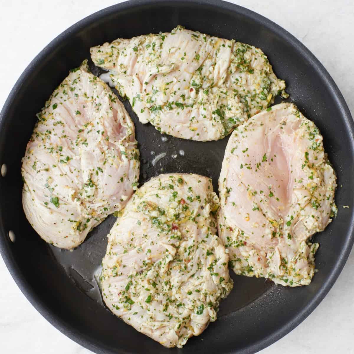 Marinated chicken in a skillet.