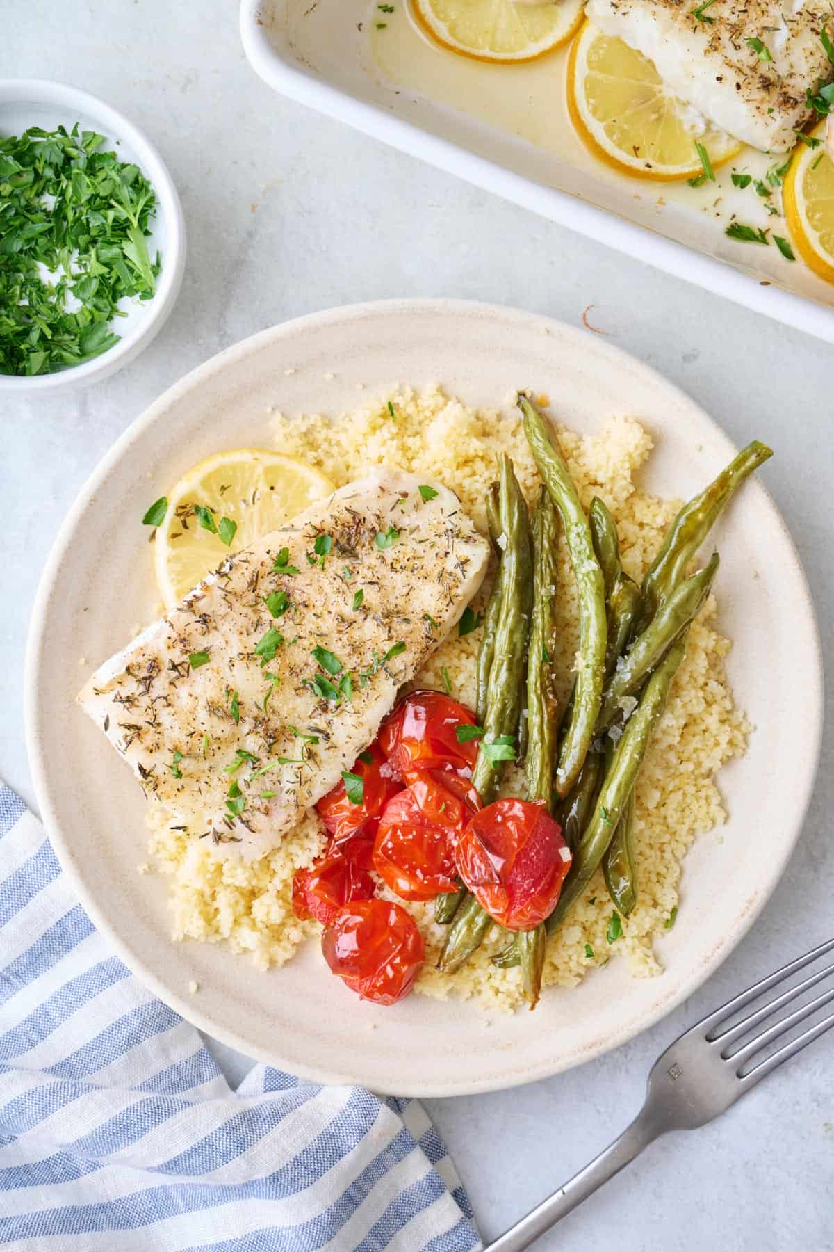 Oven baked cod served over couscous with roasted cherry tomatoes and green beans.