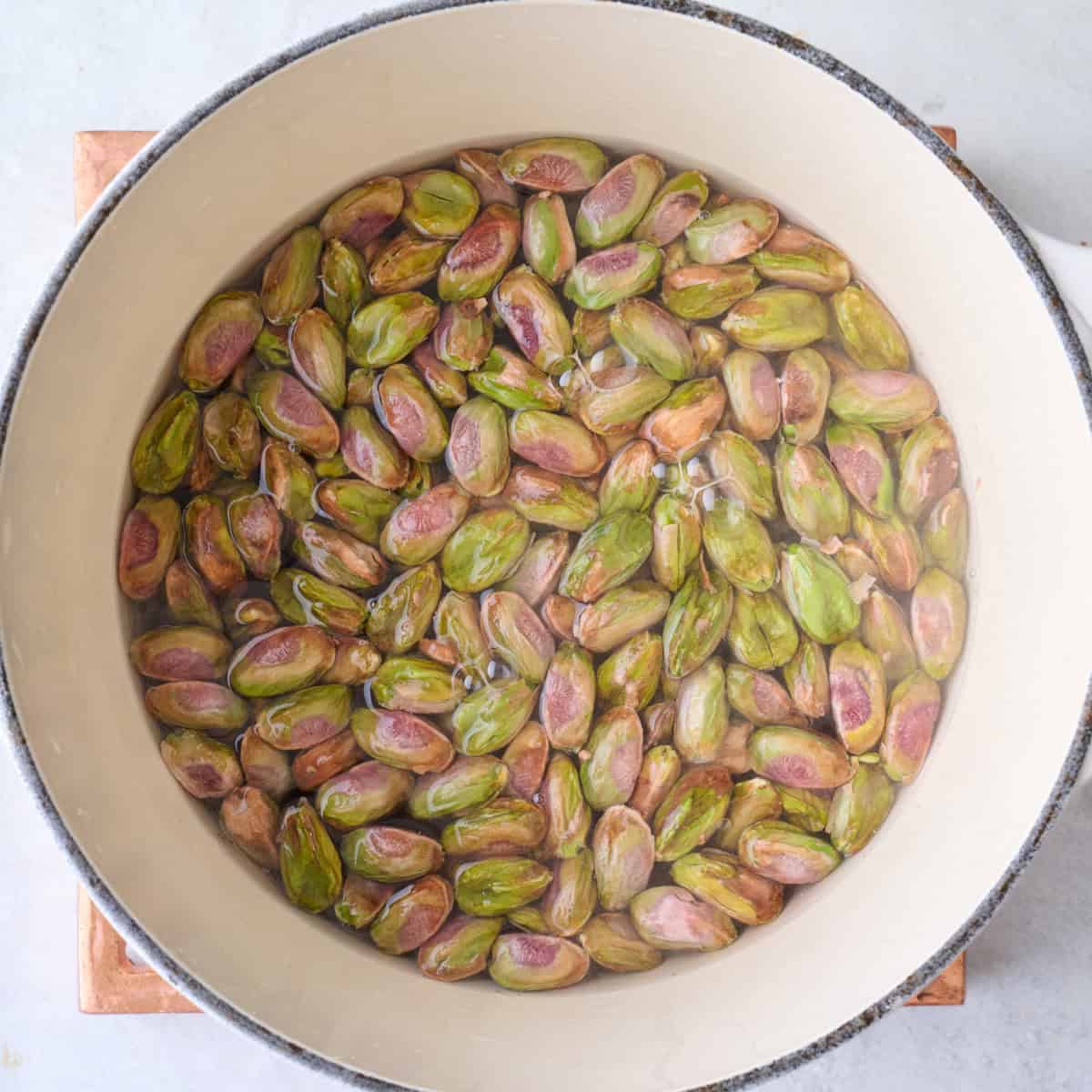 Shelled pistachios in a pot covered with water.