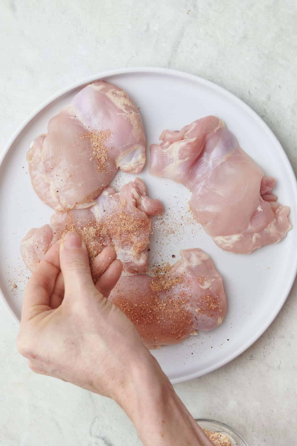 Add seasoning to chicken on a plate.