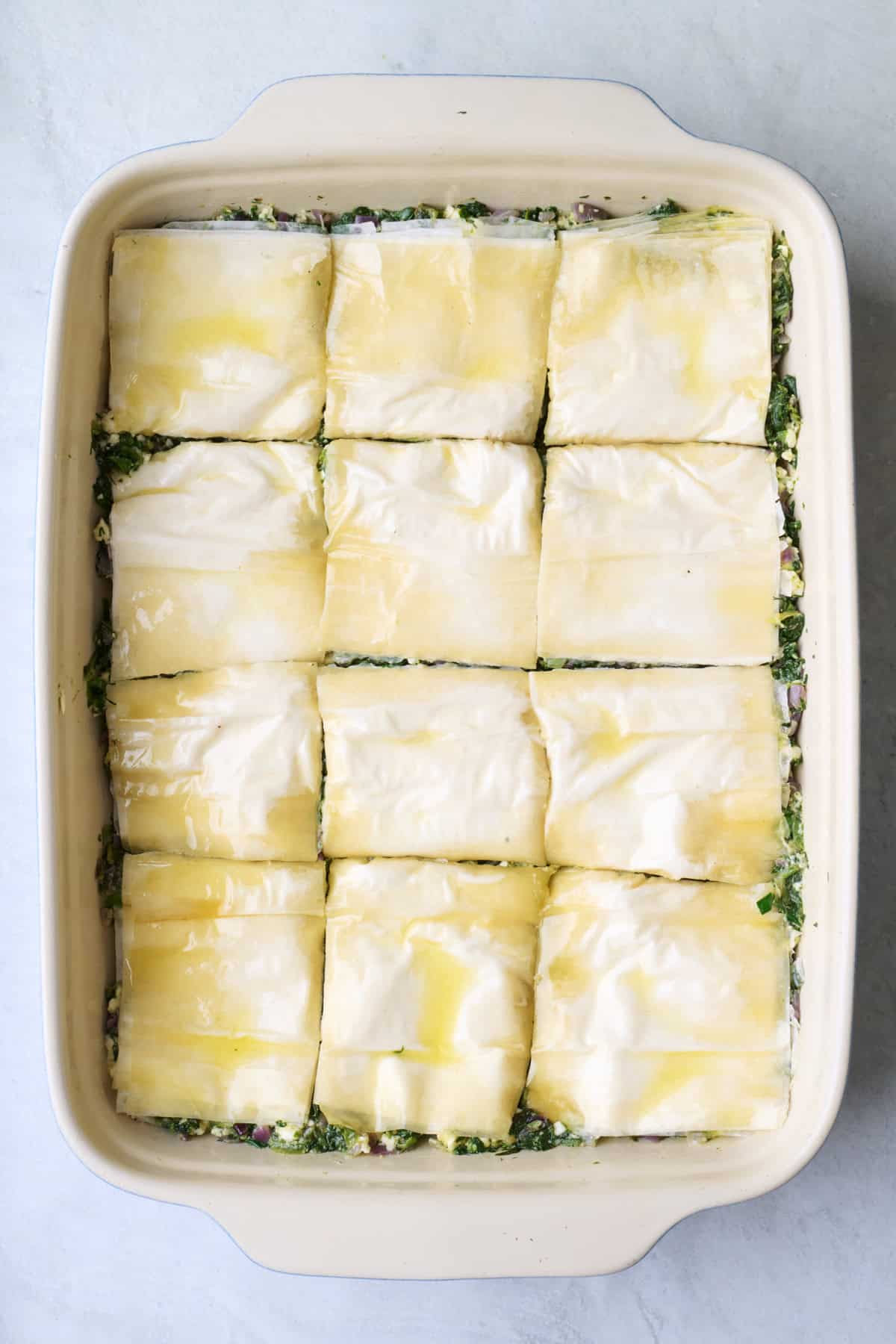 Remaining trimmed phyllo added with oil spread on top and cut into 12 pieces.