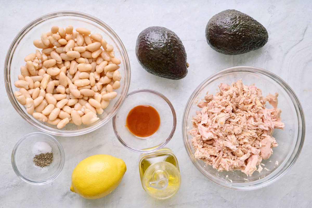 Ingredients for recipe: white beans, avocados, salt and pepper, lemon, oil, hot sauce, and tuna.