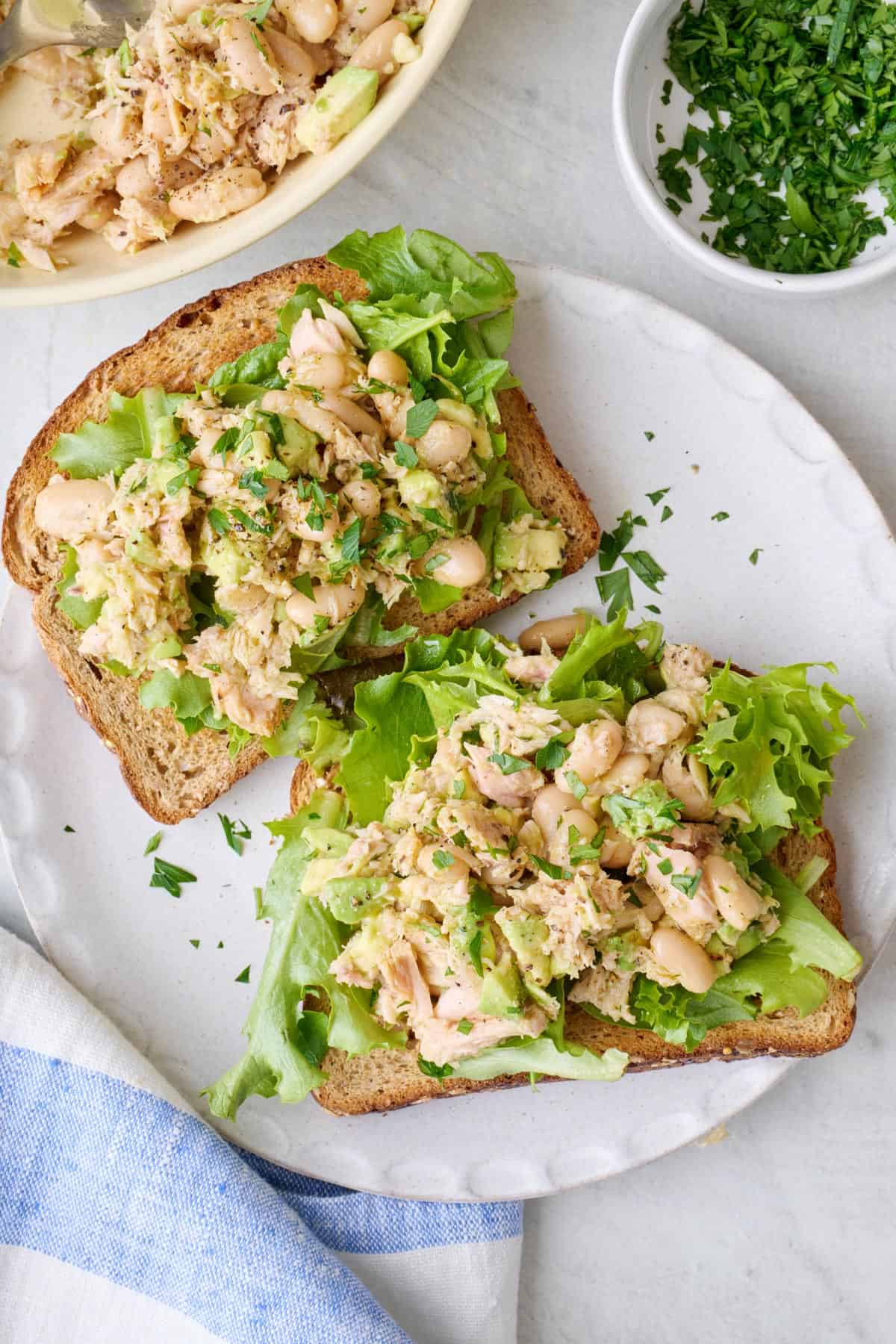 White bean tuna salad served open faced with mixed greens on toast.