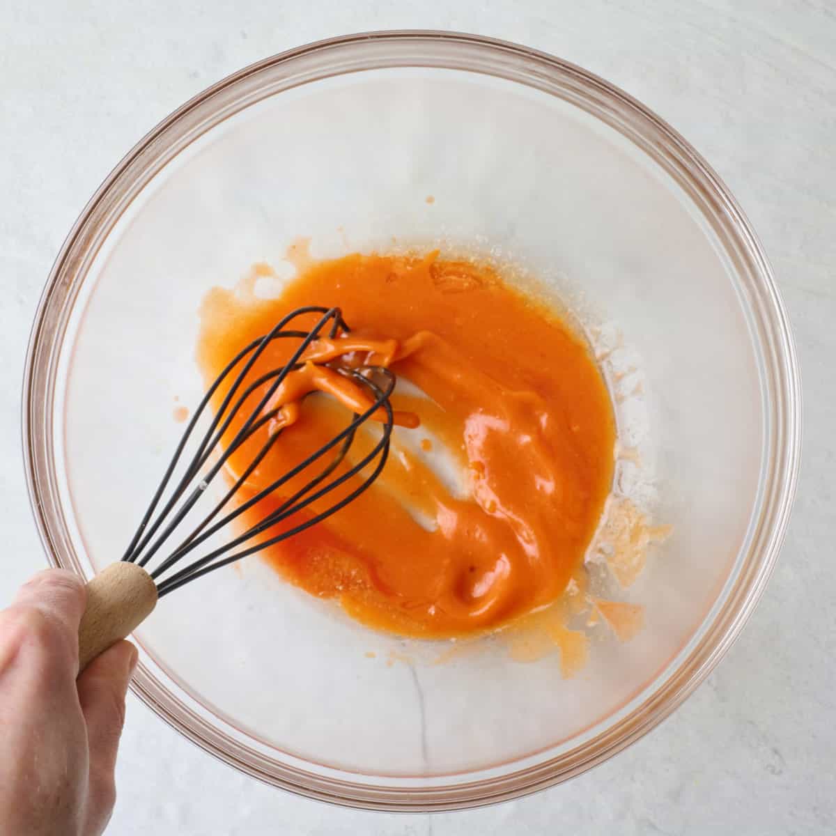 Whisking butter and hot sauce together.