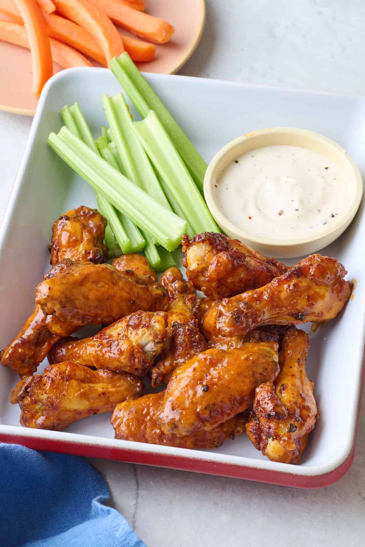 Crispy air fried buffalo wings on a platter with celery sticks and ranch.