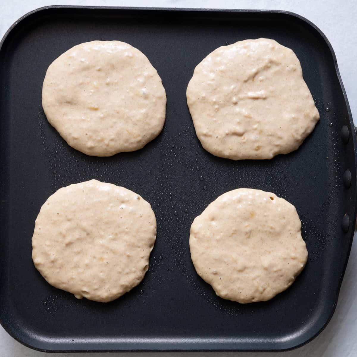 Pancakes on griddle before cooked.