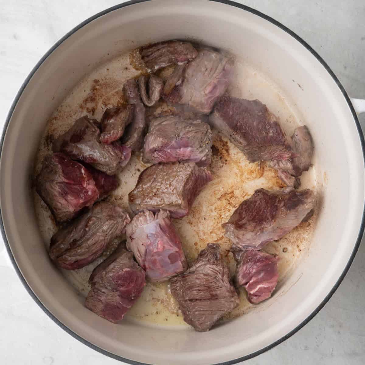 Seasoned beef in Dutch oven partially seared.