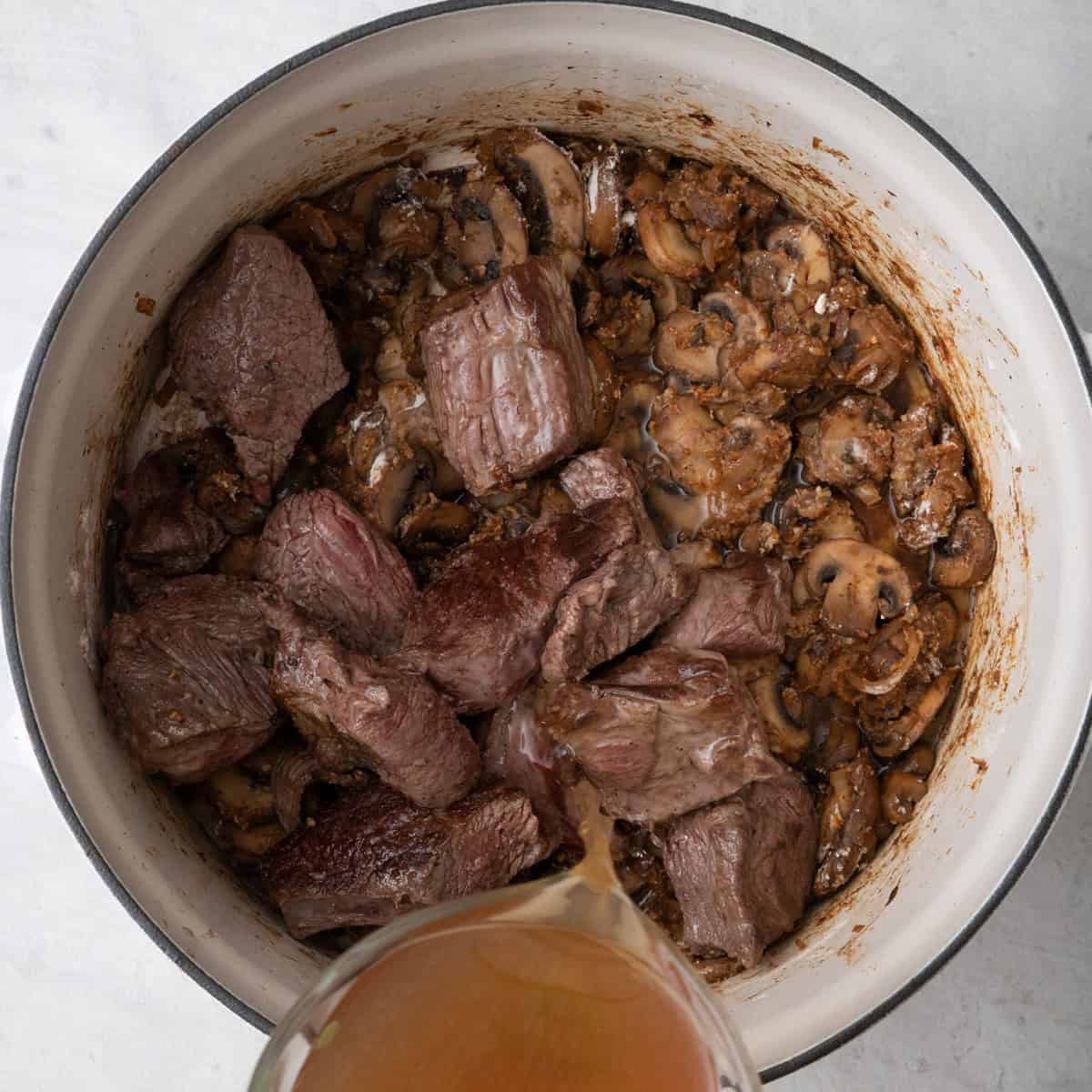 Flour, paprika and dijon added and coating the veggies with beef added back, pouring in stock.