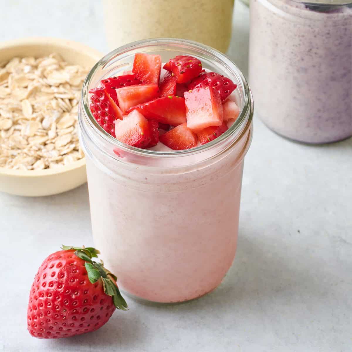 Strawberry blended overnight oats in a small jar topped with fresh chopped strawberries.