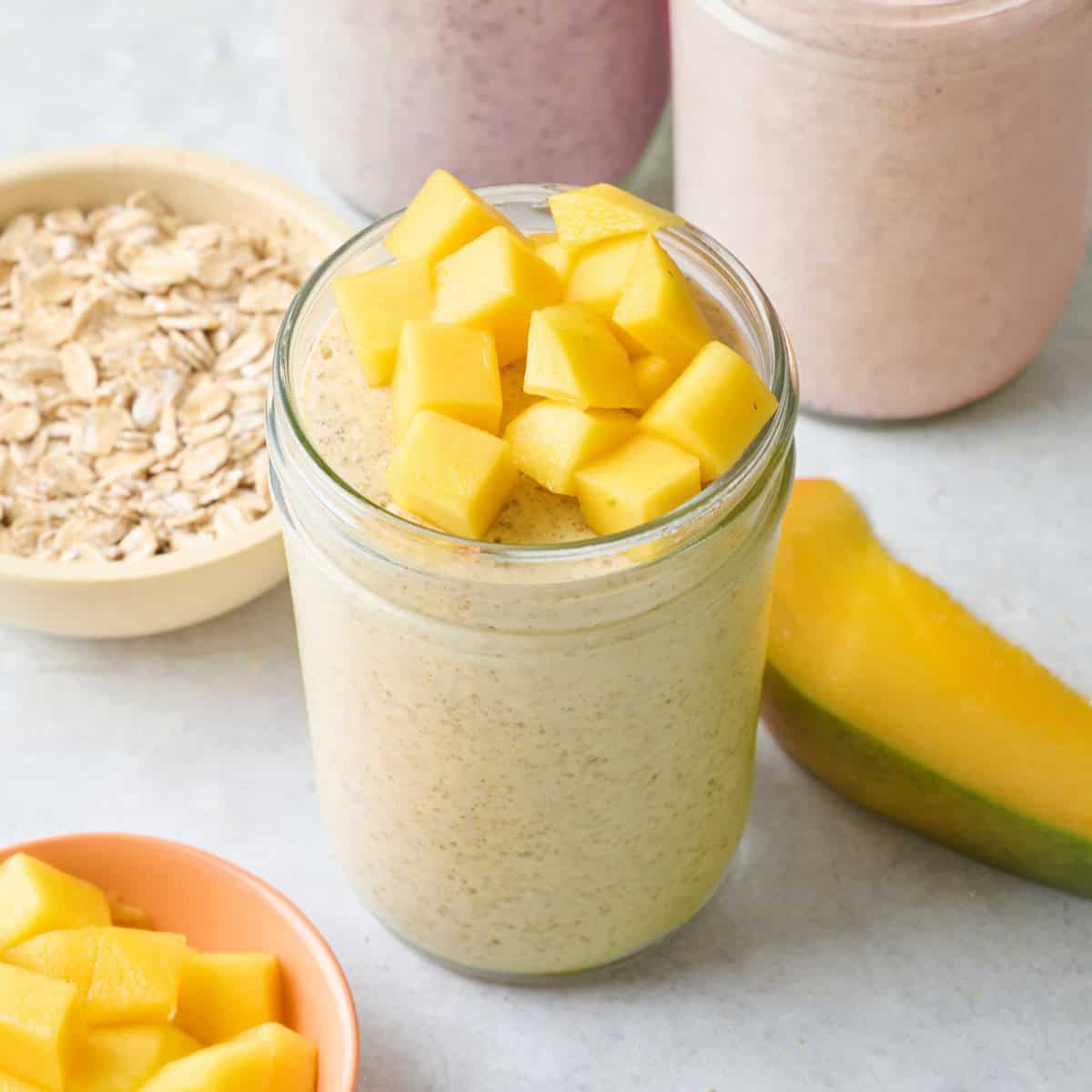 Mango blended overnight oats in a small jar topped with fresh chopped mangoes.