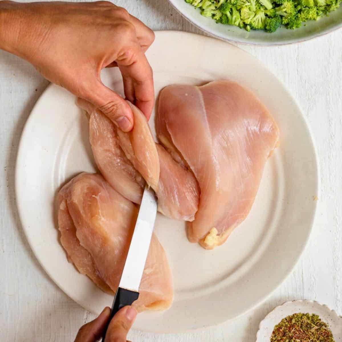 Butterflying chicken breast with sharp knife.