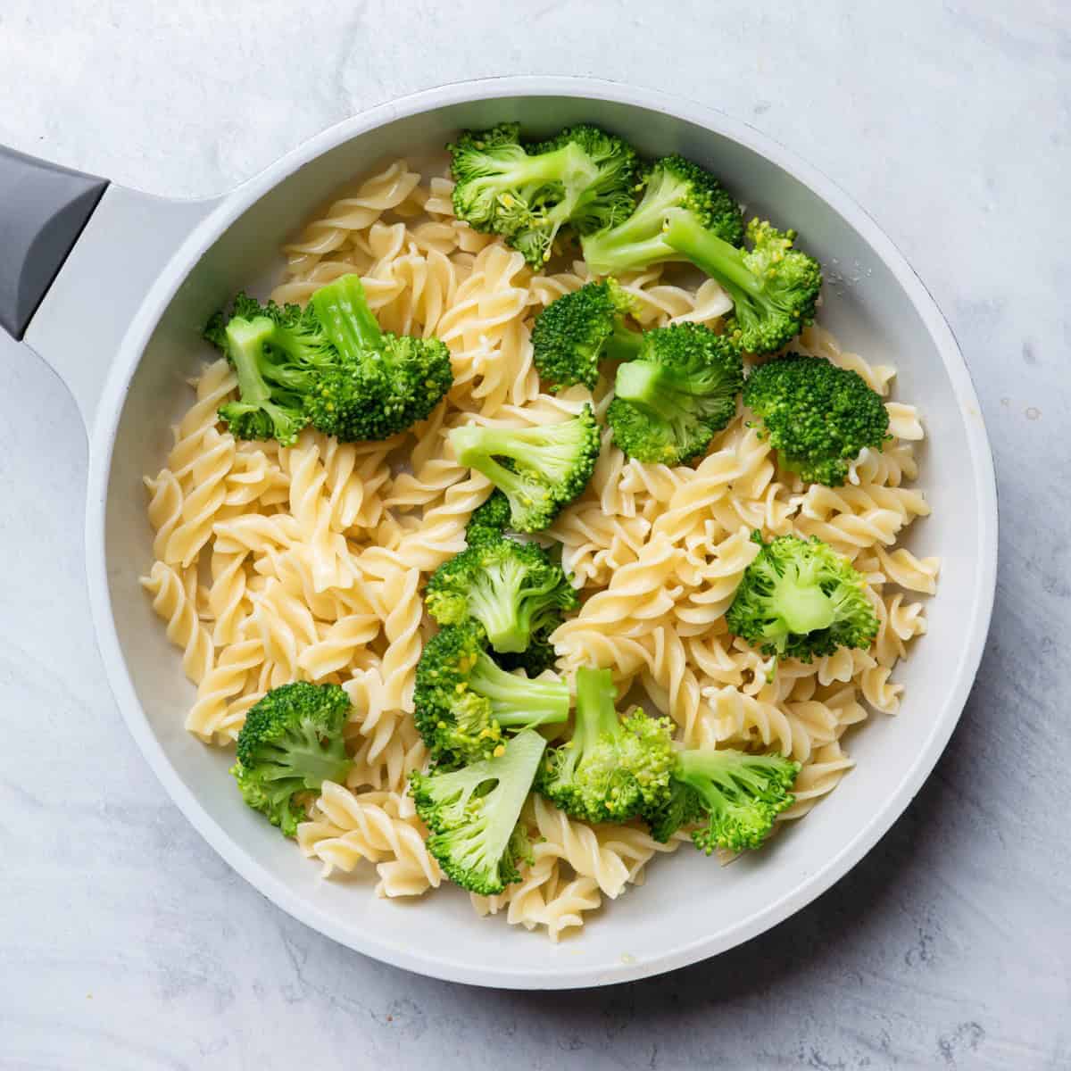 Cooked broccoli added on top of pasta.