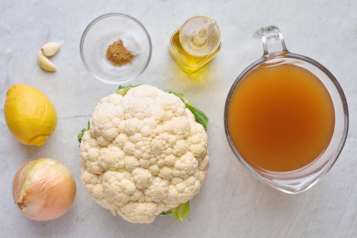 Ingredients for recipe: lemon, garlic, onion, salt and cumin, oil, cauliflower, and broth.