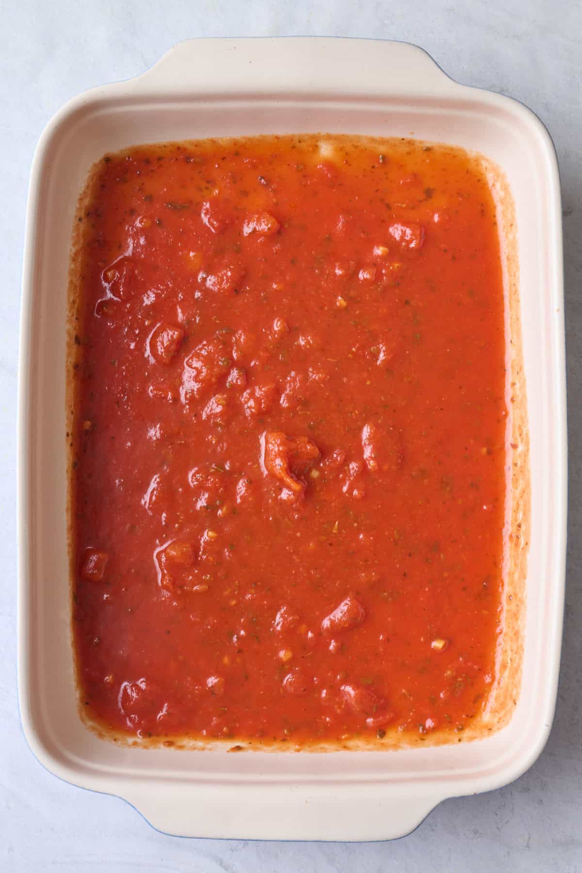 Half of sauce spread into a baking dish.