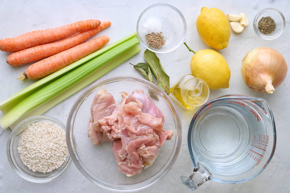 Ingredients for recipe: carrots, celery, rice, boneless skinless chicken thighs, bay leaves, salt and pepper, oil, lemon, garlic, parsley, onion, and water.