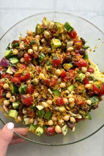 Easy crispy rice salad with chickpeas, tomatoes, olives, cucumbers, onions and a citrus salad dressing.