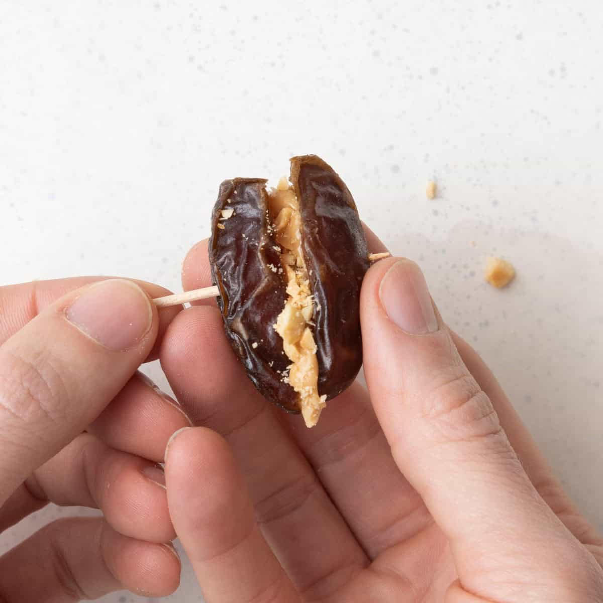 Piercing nut stuffed date with a toothpick.