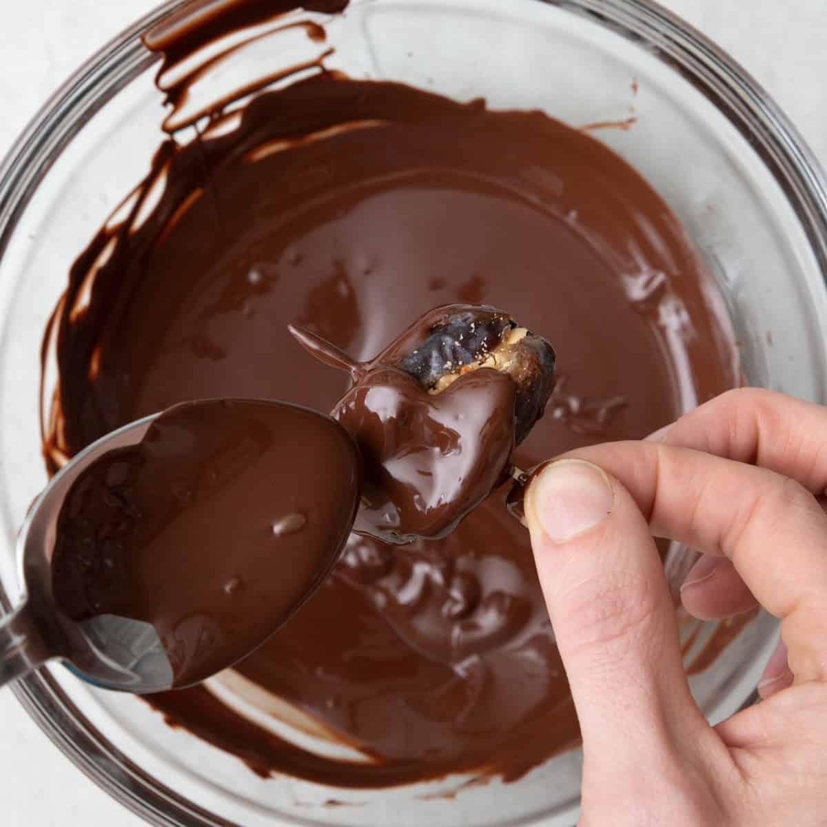 Spoon pouring chocolate over recipe to fully coat.