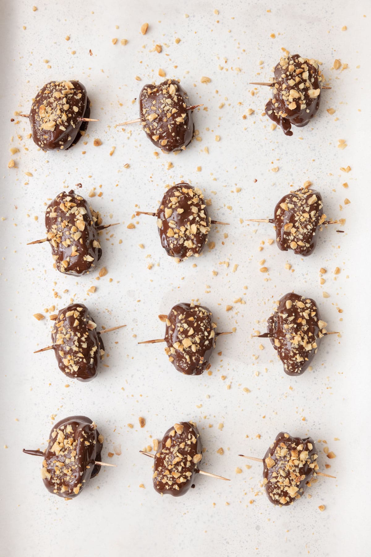 Recipe on parchment paper after coating in chocolate and sprinkling extra nuts on top.