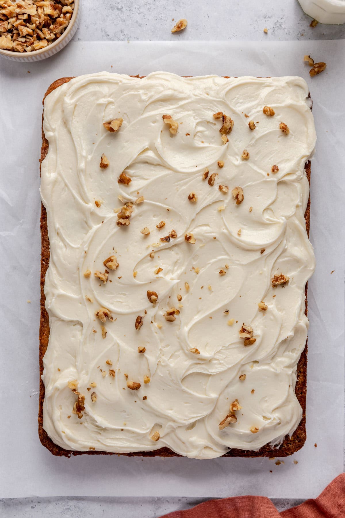 Carrot cake removed from the pan, topped with cream cheese frosting and a few extra finely chopped walnuts on top.